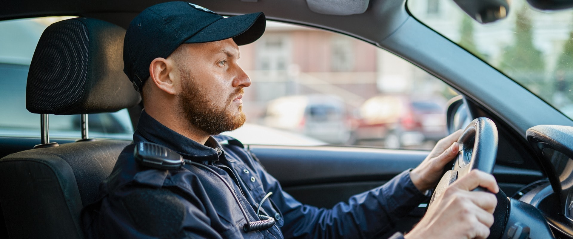 Männlicher Polizist in Uniform posiert im Auto